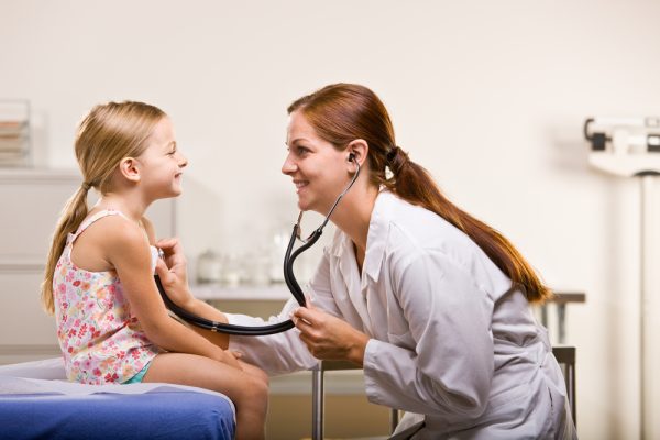 Doctor giving girl checkup in doctor office